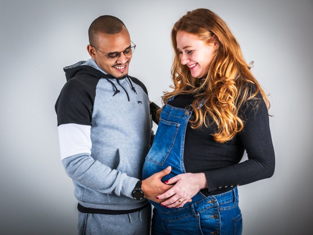 Zwanger koppel handen op buik en kijken liefde vol naar de buik